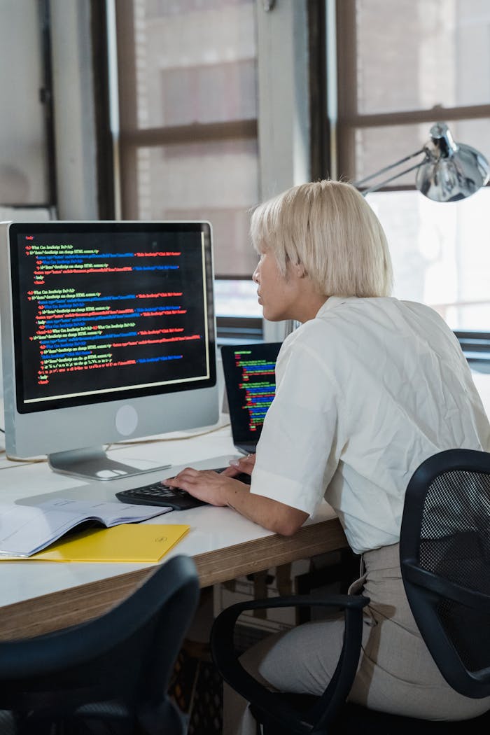 our-story Woman engaged in software programming in a contemporary office setting with multiple screens.