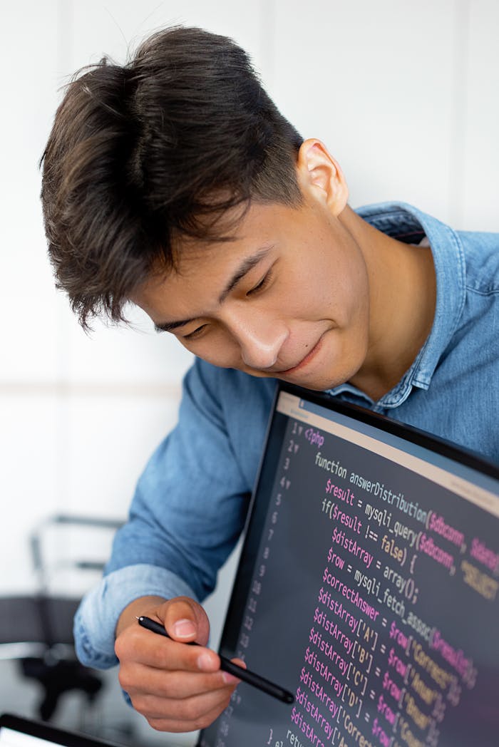 services-04 A young man smiles while programming in a modern office environment.